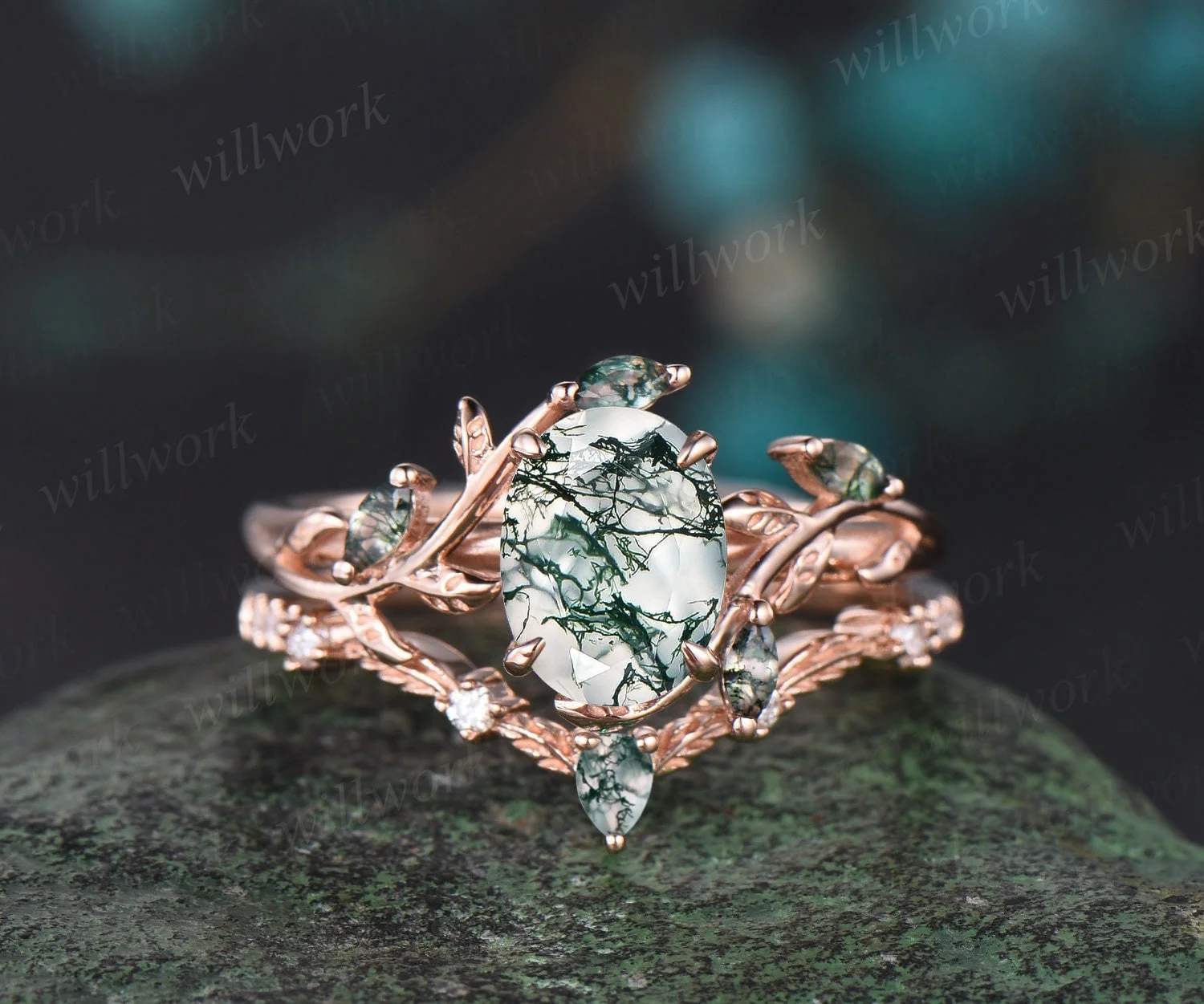 WillWork oval moss agate engagement ring and leaf wedding band in rose gold on a mossy stone